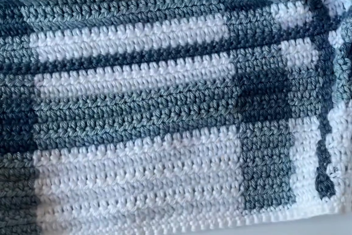 Close-up of the crochet plaid with thin dark blue vertical lines