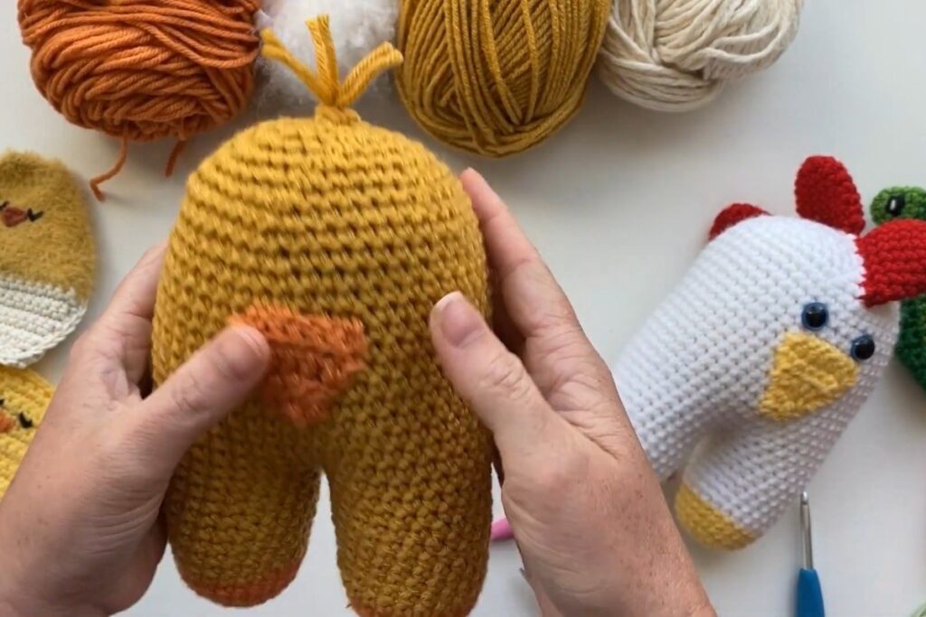 Finished yellow crochet amigurumi chick with orange feet and yarn hair by A Crafty Concept