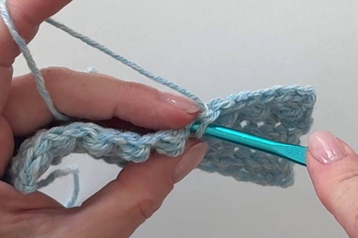Working berry stitches with a crochet hook on a blue practice swatch