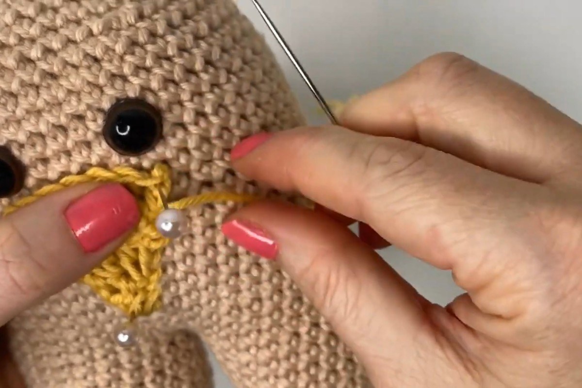 Pinning and sewing the crochet beak onto the amigurumi chick