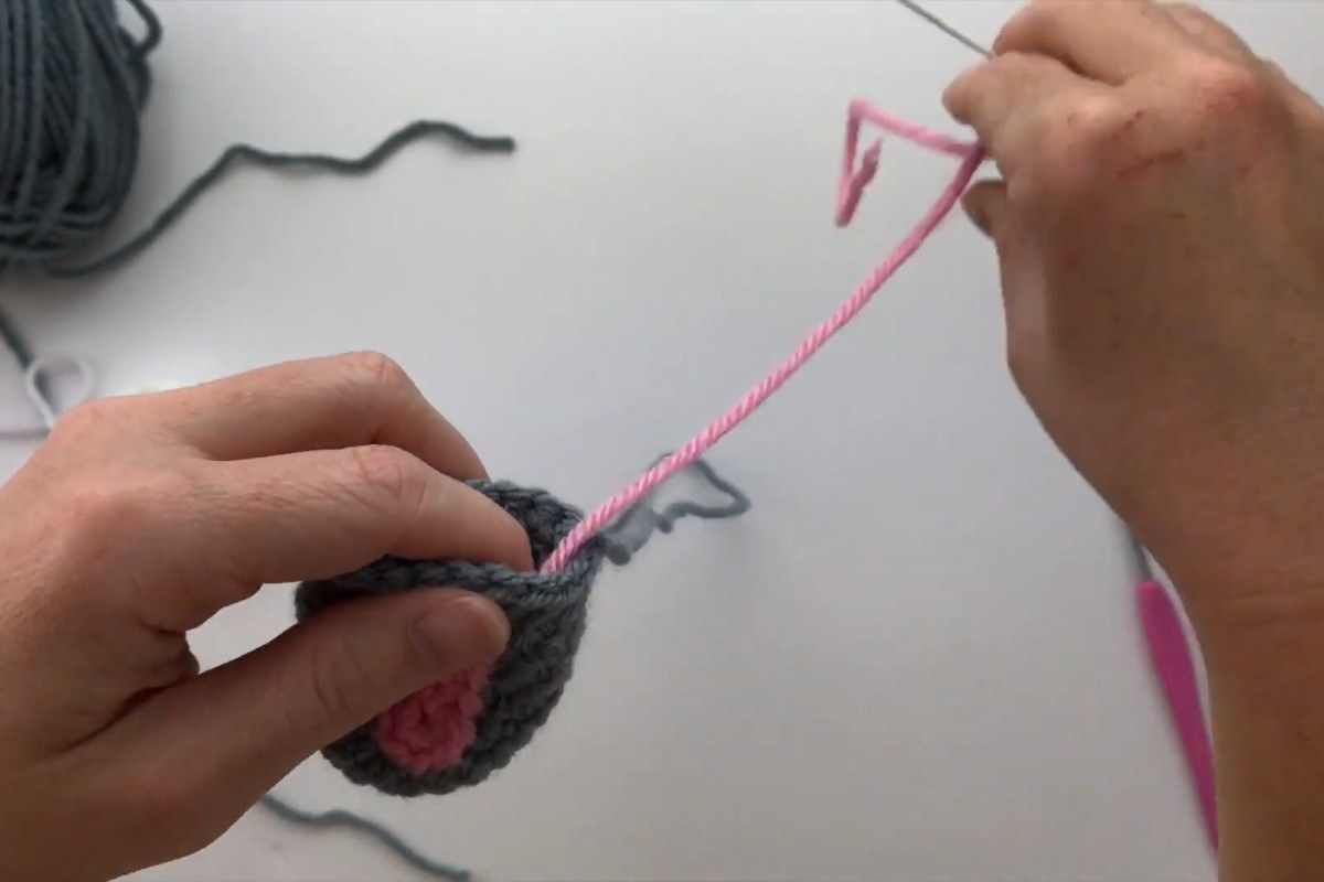 Sewing the pink inner ear onto a gray crochet cow ear