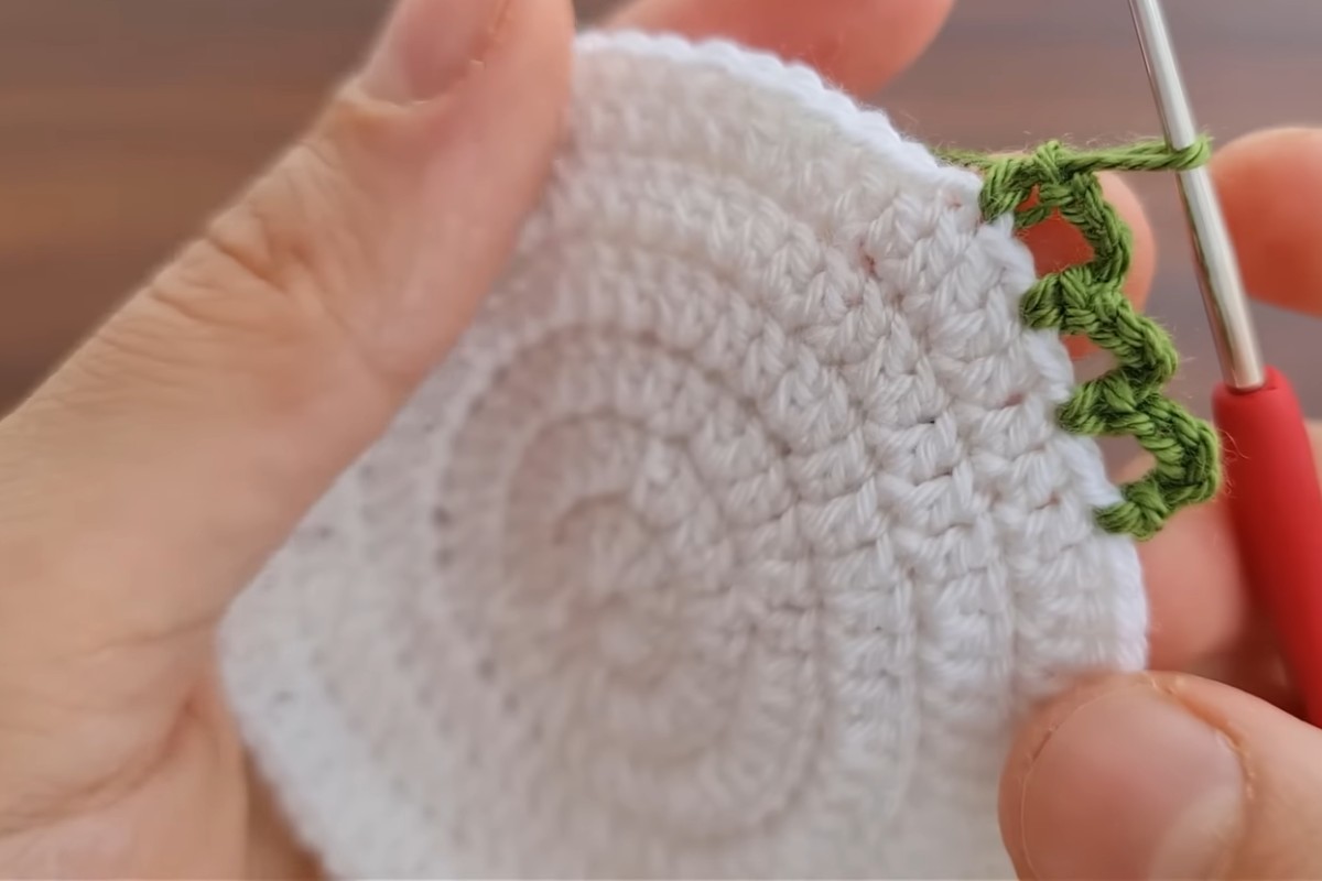 White double crochet base of the flower coaster with the green scalloped edge starting, by Knitting Love