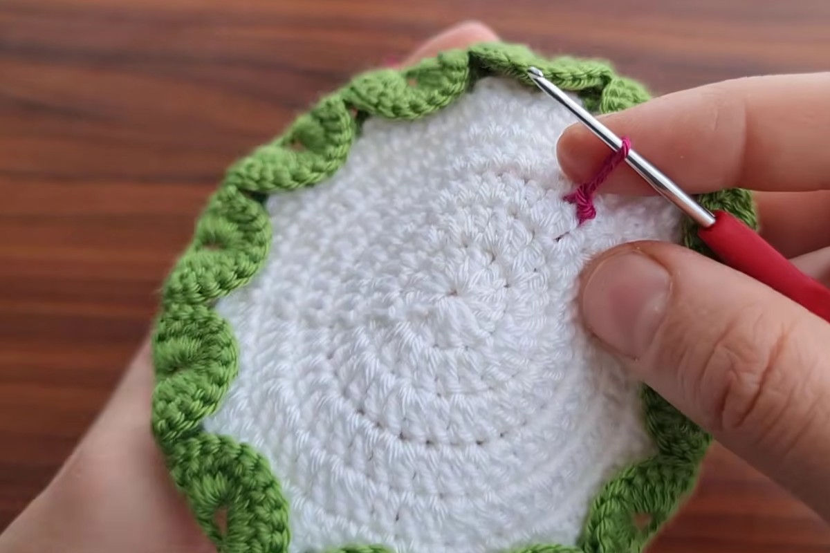 Green scalloped border around the white circle of the crochet flower motif