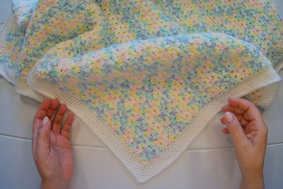 Finished easy crochet baby blanket in pastel ombre yarn with a white border by Crochet Cabin