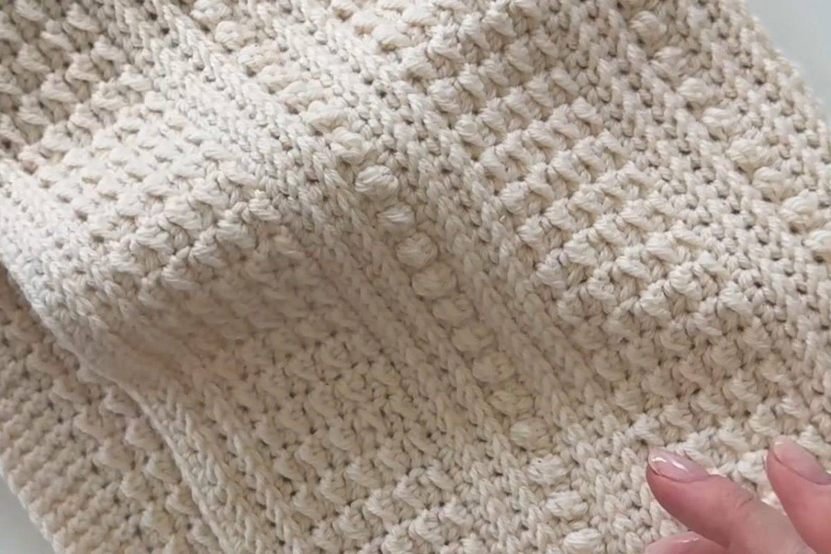 Close-up of the even moss and berry stitch texture on a cream crochet scarf