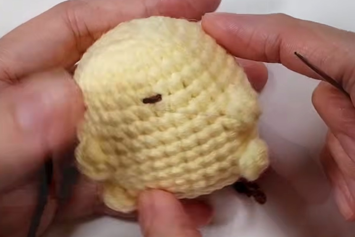 Embroidering the face on the yellow pudding pup amigurumi