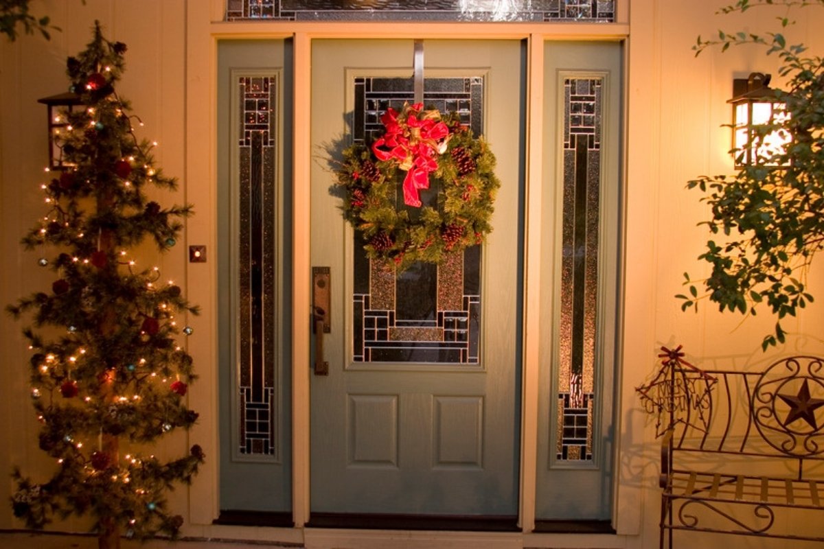 Christmas entryway with a wreath on the front door, a lit tree and a lantern