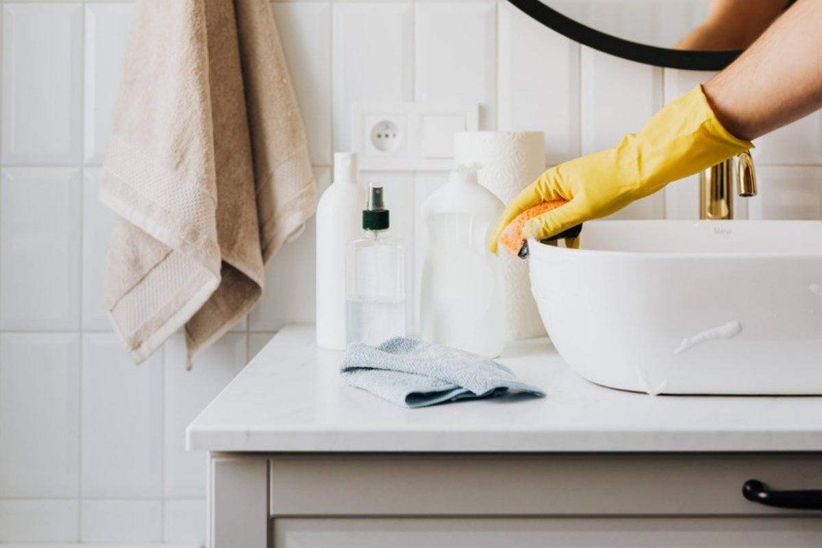 Cleaning a bathroom sink while wearing yellow rubber gloves