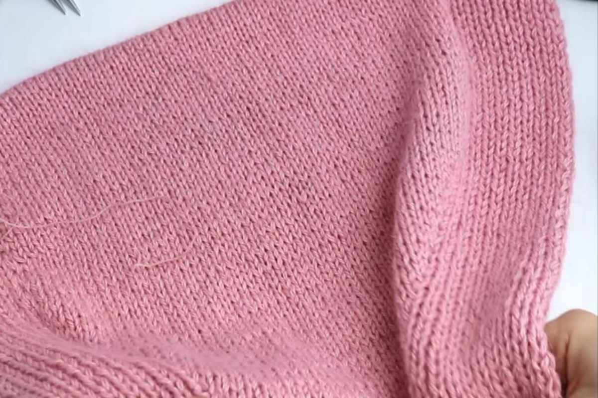 Back of a pink knit hood showing the curved shaping in stockinette stitch