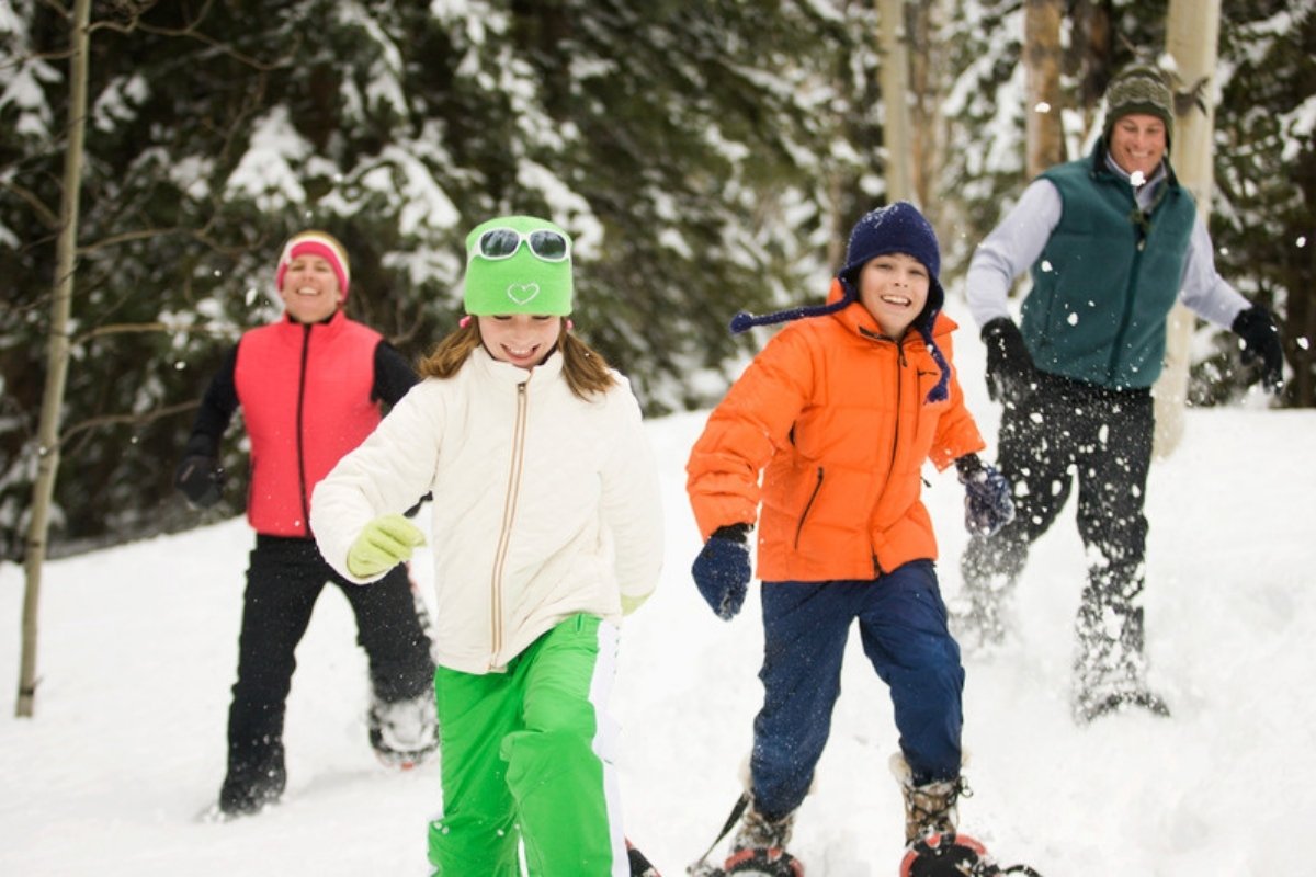 Family snowshoeing together through a snowy forest