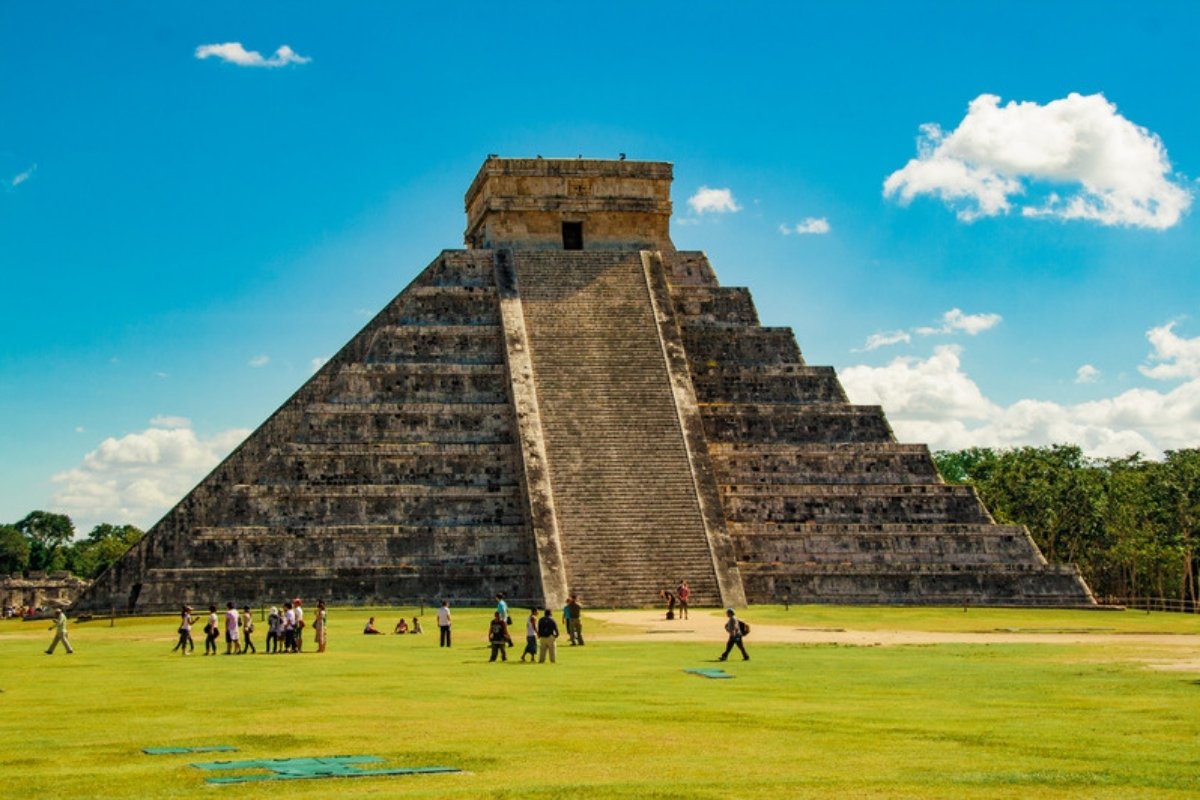 El Castillo pyramid at Chichen Itza with visitors on the lawn